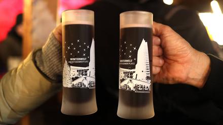Zwei Menschen prosten sich mit Glühwein zu.