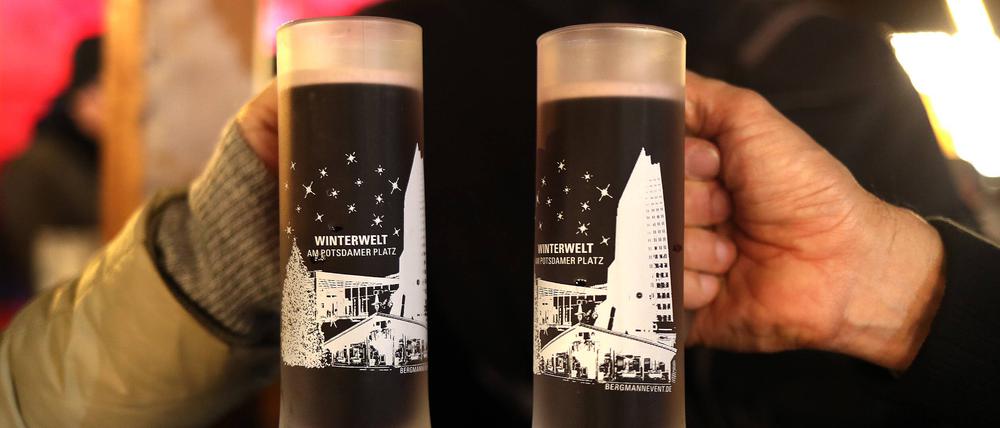 Zwei Menschen prosten sich mit Glühwein zu.
