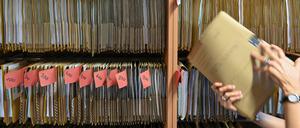 Eine Mitarbeiterin einer Behörde greift an einem Regal nach einer Akte (Symbolbild).