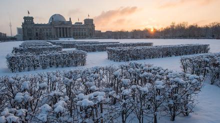 Die Morgensonne geht am 29.12.2014 in Berlin vor dem in Schnee gehüllten Reichstag auf.