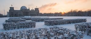 Die Morgensonne geht am 29.12.2014 in Berlin vor dem in Schnee gehüllten Reichstag auf.