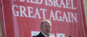Mike Huckabee (r), der ehemalige Gouverneur des US-Bundesstaates Arkansas, spricht zu Journalisten im Rahmen einer offiziellen Ecksteinlegung, in einem neuen Wohnhauskomplex in der jüdischen Siedlung im Westjordanland. Im Hintergrund ist ein Banner mit der Aufschrift: «Baut Israel wieder großartig» zu sehen.