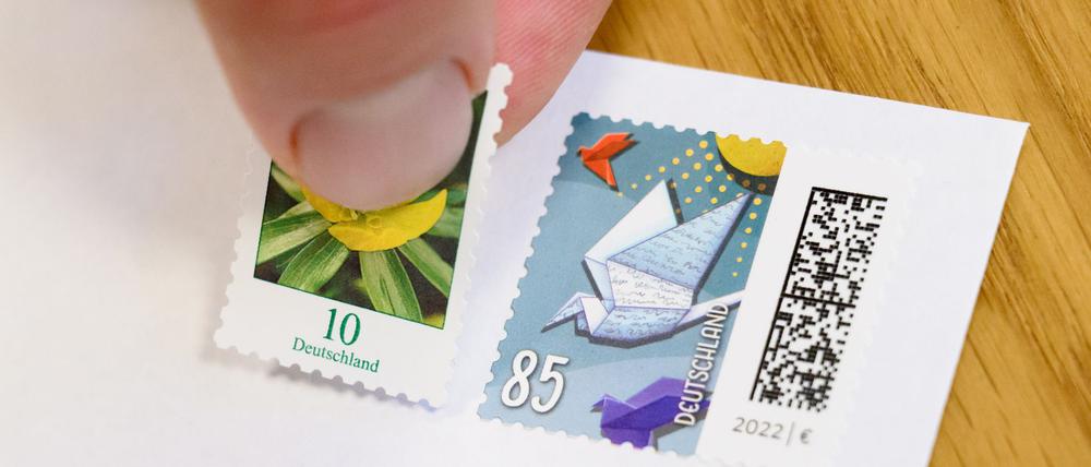 Eine 10-Cent-Briefmarke wird neben eine 85-Cent-Briefmarke geklebt (gestellte Szene).