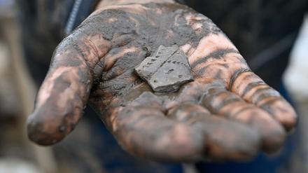 Eine 7000 Jahre alte Scherbe, die am Fundplatz einer 7500 Jahre alten Siedlung ausgegraben wurde, liegt in der Hand einer Archäologiestudentin. Der Siedlungsplatz gehört zur Linearbandkeramischen Kultur. 