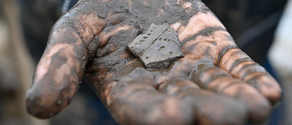 Eine 7000 Jahre alte Scherbe, die am Fundplatz einer 7500 Jahre alten Siedlung ausgegraben wurde, liegt in der Hand einer Archäologiestudentin. Der Siedlungsplatz gehört zur Linearbandkeramischen Kultur.