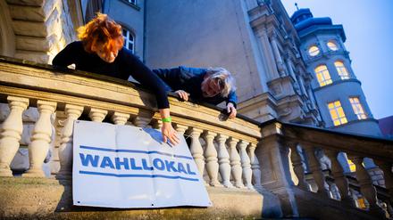 Zwei Wahlhelfer hängen am Wahllokal im Carl-von-Ossietzky-Gymnasium in Berlin-Pankow vor Wahlbeginn ein Hinweisschild auf. Wegen zahlreicher Pannen muss die Bundestagswahl 2021 in Berlin teilweise wiederholt werden.