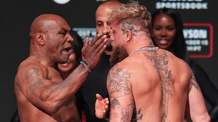 15.11.2024, USA, Irving: Boxer Mike Tyson (l) ohrfeigt Jake Paul beim Wiegen vor ihrem Schwergewichtskampf.