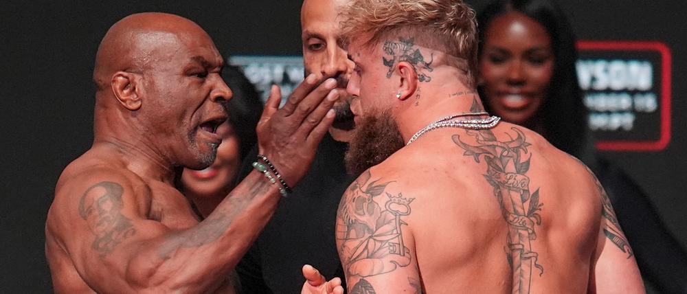15.11.2024, USA, Irving: Boxer Mike Tyson (l) ohrfeigt Jake Paul beim Wiegen vor ihrem Schwergewichtskampf.