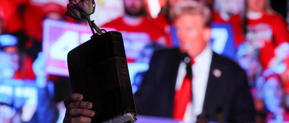 Ein Trump-Unterstützer hält bei einer Wahlkampfveranstaltung in Michigan eine Bibel und eine Rose hoch. 