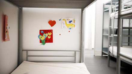 Kinderbilder kleben an einer Wand über einem Bett in einem Wohnbereich in einem Unterkunftskomplex im Ankunftszentrum Tegel.