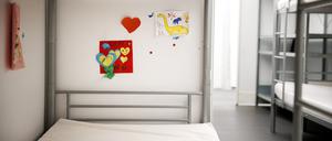 Kinderbilder kleben an einer Wand über einem Bett in einem Wohnbereich in einem Unterkunftskomplex im Ankunftszentrum Tegel.