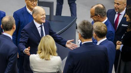 Bundeskanzler Olaf Scholz (SPD) im Gespräch mit Friedrich Merz (CDU) und Christian Lindner (FDP) im Bundestag. 