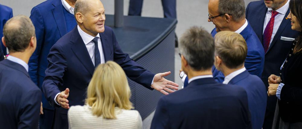 Bundeskanzler Olaf Scholz (SPD) im Gespräch mit Friedrich Merz (CDU) und Christian Lindner (FDP) im Bundestag. 