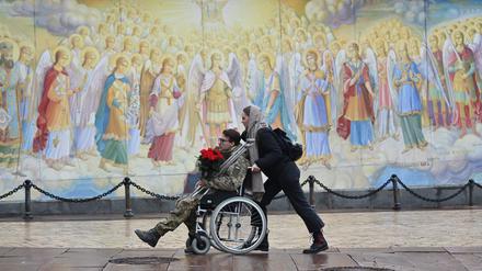 A girl pushes the wheelchair of a wounded Ukrainian serviceman in Kyiv.