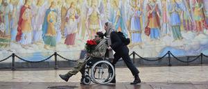 A girl pushes the wheelchair of a wounded Ukrainian serviceman in Kyiv.