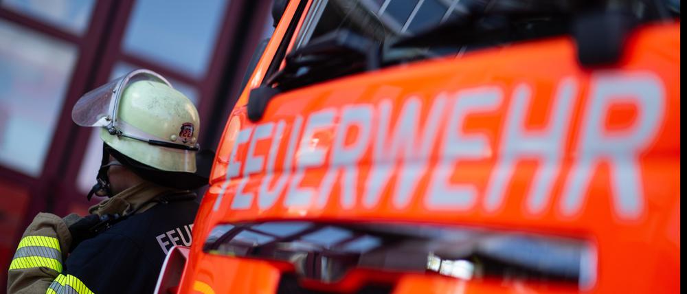 Eine Einsatzkraft der Feuerwehr steht neben einem Einsatzfahrzeug der Feuerwehr