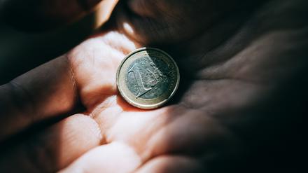 Hand and one euro coin in dramatic light.