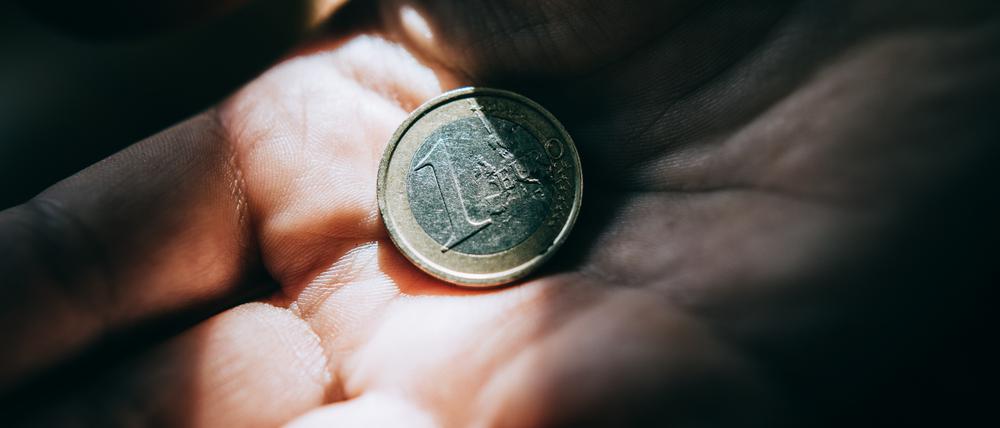 Hand and one euro coin in dramatic light.
