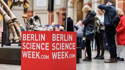 Besucher der Berlin Science Week 2022 stehen neben einem Logo-Würfel im Museum für Naturkunde. 