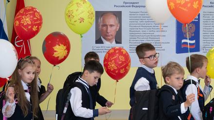 Schulkinder gehen an einem Putin-Plakat vorbei.