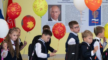 Schulkinder gehen an einem Putin-Plakat vorbei.