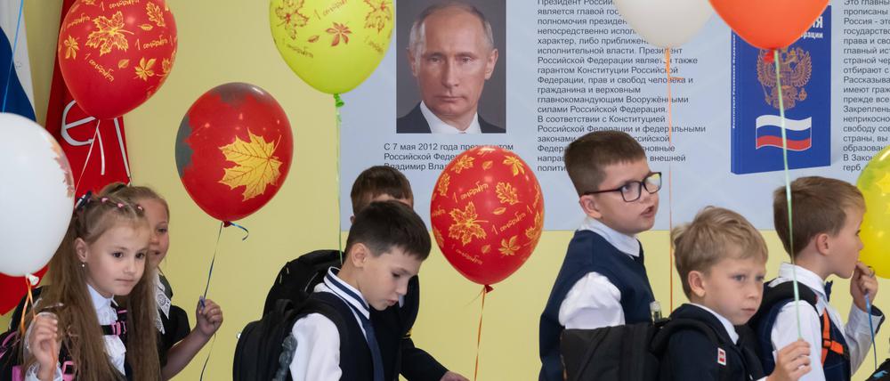 Schulkinder gehen an einem Putin-Plakat vorbei.
