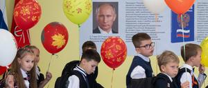 Schulkinder gehen an einem Putin-Plakat vorbei.