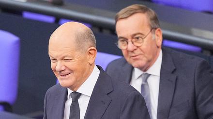 Bundeskanzler Olaf Scholz (SPD) steht lächelnd vor seiner Regierungserklärung im Plenum des Bundestags vor Boris Pistorius (SPD), Bundesminister der Verteidigung. 