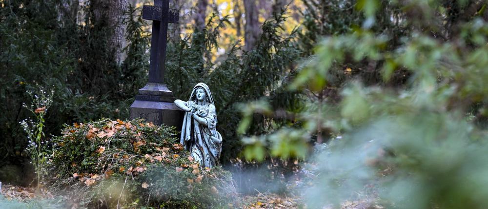 Eine Figur und ein Kreuz an einem Grab auf dem St. Elisabeth-Friedhof.