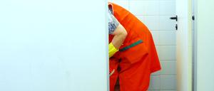 Eine Putzfrau reinigt in einer Schule die Toiletten. 