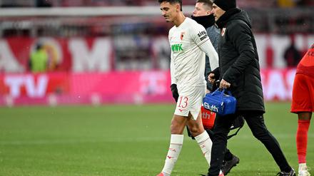 Augsburgs Verteidiger Dimitrios Giannoulis (l)  geht verletzt vom Platz.