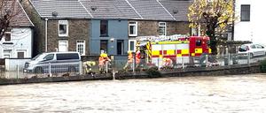 Feuerwehrleute lassen Wasser in einen angeschwollenen Fluss, während der Sturm „Bert“ über Großbritannien hinwegfegt.