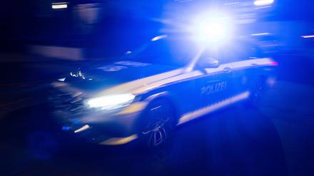 Ein Polizeifahrzeug fährt mit Blaulicht an einem Gebäude vorbei. 