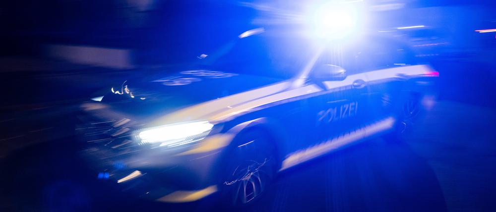Ein Polizeifahrzeug fährt mit Blaulicht an einem Gebäude vorbei.
