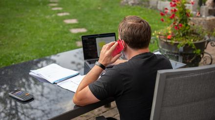 Ein Mann sitzt im Garten und arbeitet am Laptop (Symbolbild).