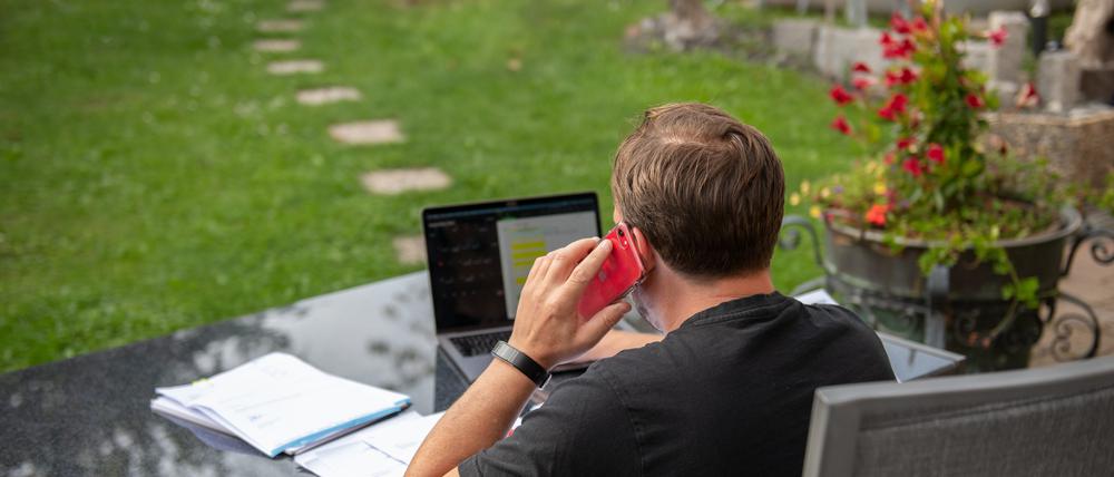 Ein Mann sitzt im Garten und arbeitet am Laptop (Symbolbild).