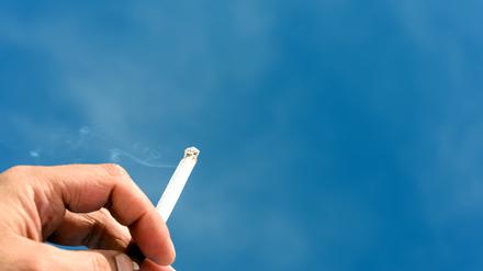 Male Hand Holding a Cigarette and Blue Sky