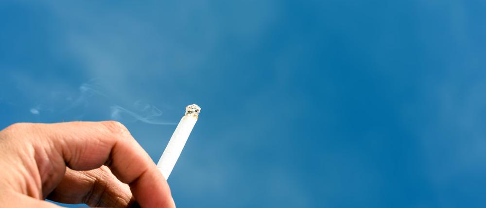 Male Hand Holding a Cigarette and Blue Sky