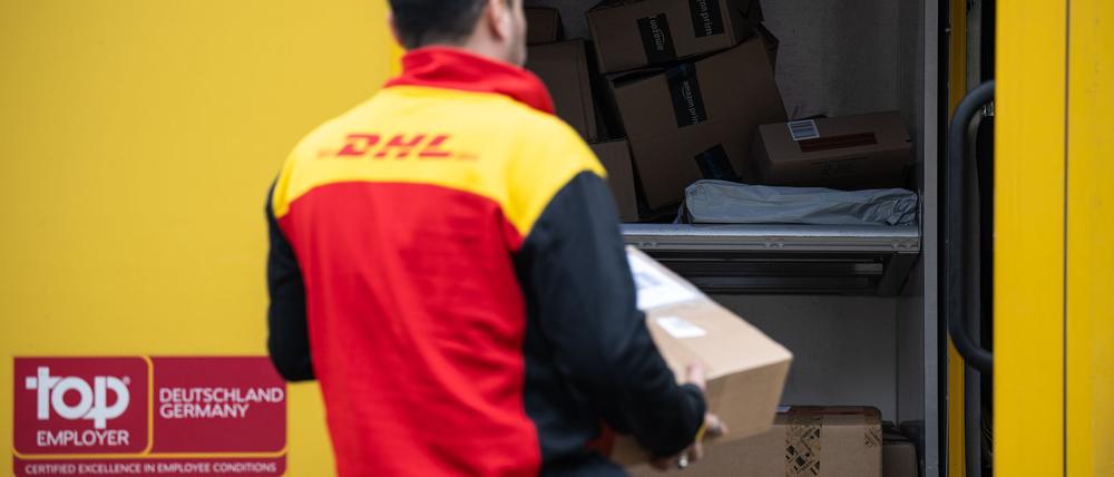 Ein Post-Mitarbeiter trägt ein Paket in einen Lieferwagen.