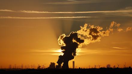 Das Kohlekraftwerk Niederaußem und umliegende Stromleitungen zeichnen sich gegen die untergehende Sonne ab.