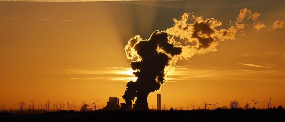 Das Kohlekraftwerk Niederaußem und umliegende Stromleitungen zeichnen sich gegen die untergehende Sonne ab.