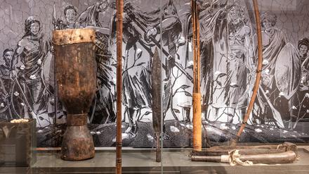 Pfeil und Bogen, Trommel und Pulverhorn in einer Ausstellungsvitrine.