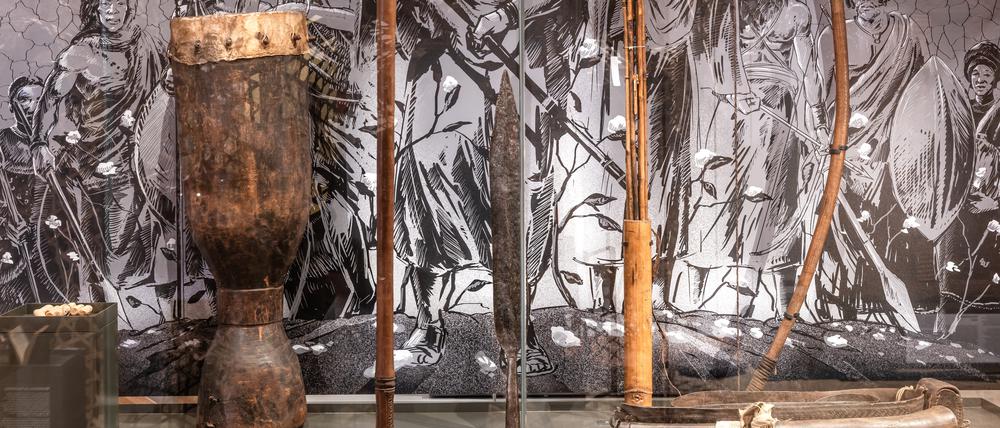 Pfeil und Bogen, Trommel und Pulverhorn in einer Ausstellungsvitrine.