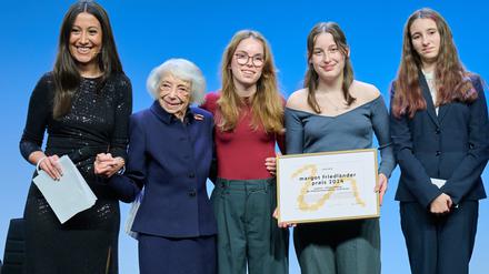 Margot Friedländer (2.v.l) übergibt Schülerinnen der Schülerzeitung „josefine“ den Margot Friedländer Schulpreis 2024, während Moderatorin Alev Doğan (l) ihre Hand hält. 