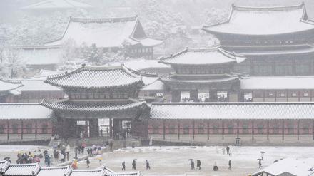 People visit Gyeongbokgung Palace amid heavy snowfall in central Seoul on November 27, 2024. South Korea's capital was blanketed on November 27 by the heaviest November snowfall since records began over a century ago, the weather agency said. (Photo by ANTHONY WALLACE / AFP)