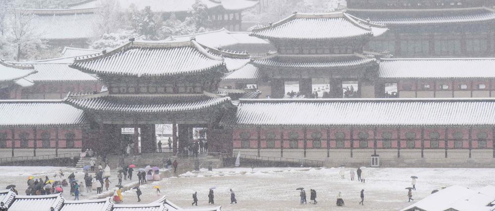 People visit Gyeongbokgung Palace amid heavy snowfall in central Seoul on November 27, 2024. South Korea's capital was blanketed on November 27 by the heaviest November snowfall since records began over a century ago, the weather agency said. (Photo by ANTHONY WALLACE / AFP)
