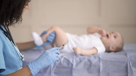 Ein Baby wird geimpft. Zu sehen ist eine Ärztin mit einer Spritze, die das Bein eines Babys festhält.