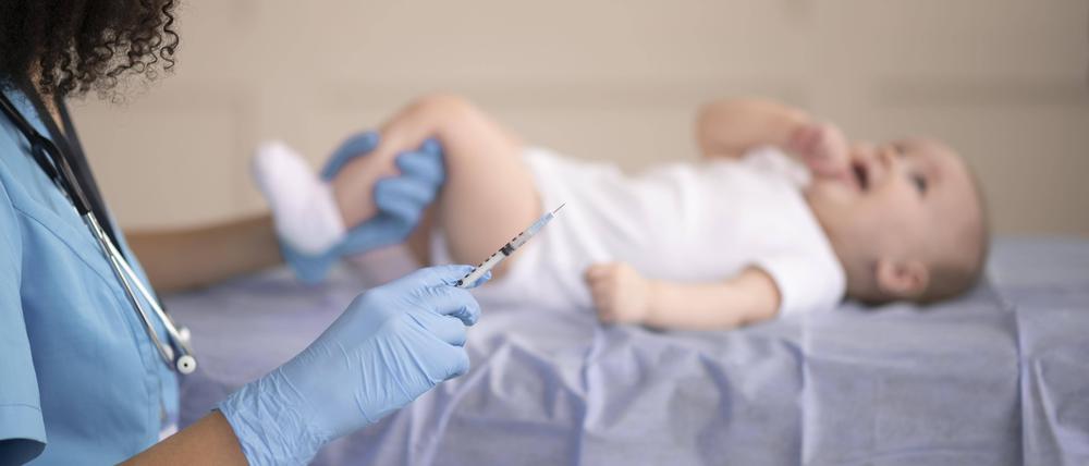 Ein Baby wird geimpft. Zu sehen ist eine Ärztin mit einer Spritze, die das Bein eines Babys festhält.