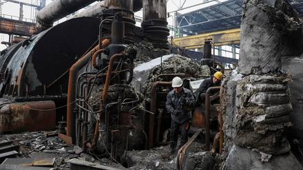 Ukrainische Arbeiter inspizieren ein beschossenes Kraftwerk.