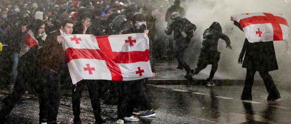 Polizeibeamte setzen einen Wasserwerfer ein, um die Menge während einer Kundgebung von Anhängern der Oppositionsparteien zu zerstreuen. 